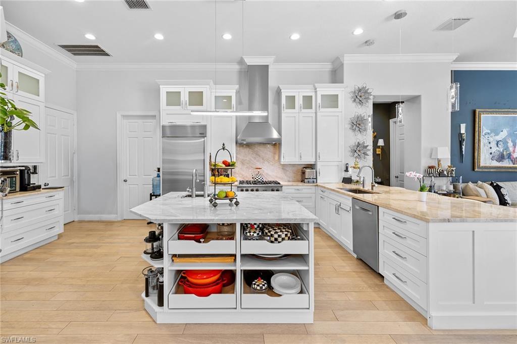 7837 Classics Drive Naples, FL 34113 - Photo 19 of 50 Kitchen featuring open shelves, glass insert cabinets, a peninsula, light stone counters, and white cabinets
