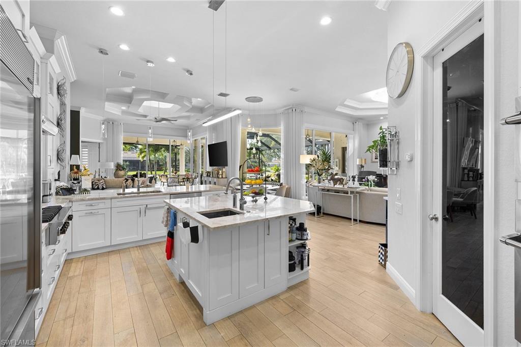 7837 Classics Drive Naples, FL 34113 - Photo 50 of 50 Kitchen with white cabinetry, a tray ceiling, light stone countertops, stainless steel appliances, and open floor plan