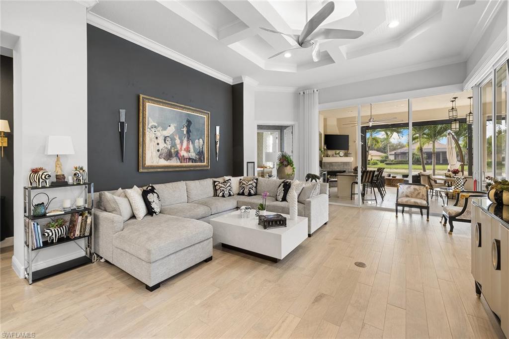 7837 Classics Drive Naples, FL 34113 - Photo 21 of 50 Living room featuring coffered ceiling, a high ceiling, light wood-type flooring, ceiling fan, and ornamental molding