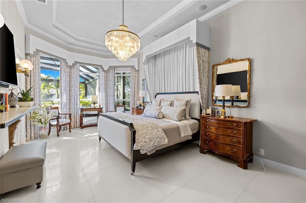 7837 Classics Drive Naples, FL 34113 - Photo 34 of 50 Bedroom featuring a chandelier, ornamental molding, a raised ceiling, and light tile patterned floors