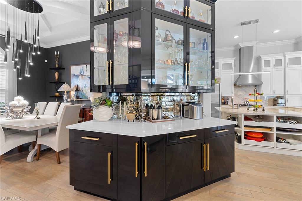 7837 Classics Drive Naples, FL 34113 - Photo 9 of 50 Kitchen with hanging light fixtures, open shelves, light wood finished floors, ornamental molding, and dark cabinets