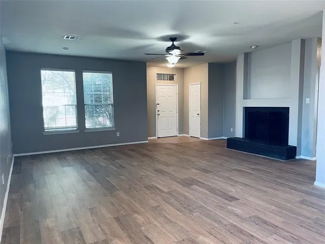 an empty room with wooden floor fireplace and windows