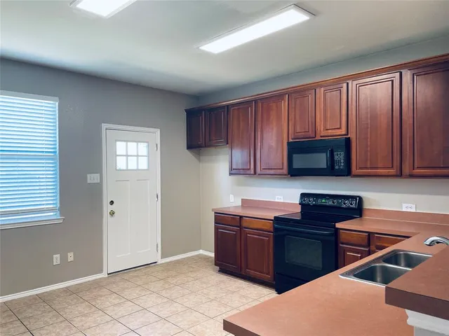 a kitchen with stainless steel appliances granite countertop a stove a sink dishwasher and a microwave oven with wooden cabinets