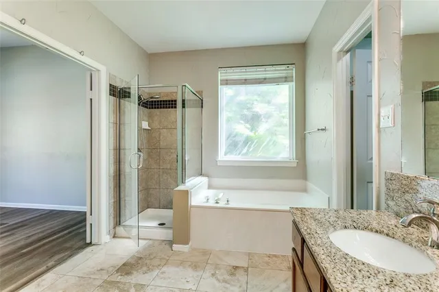 a bathroom with a granite countertop tub sink and mirror