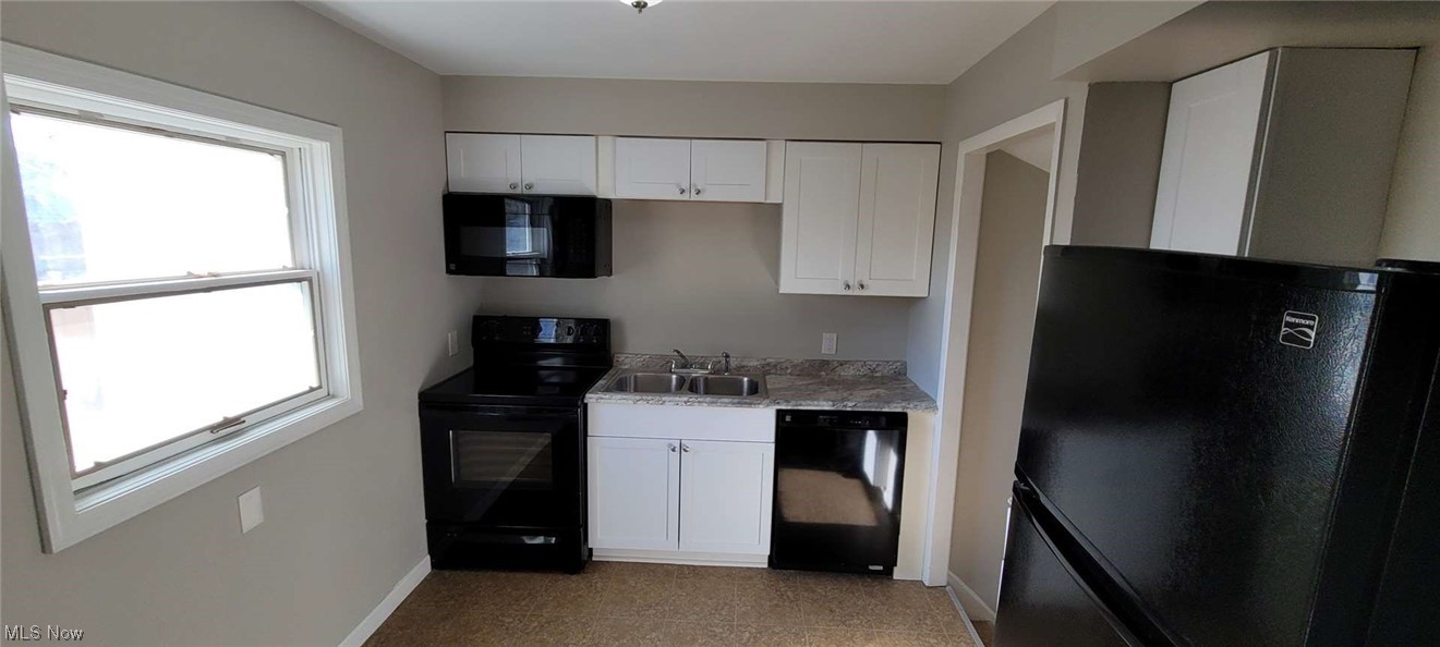 6149 North Canterbury Road Parma, OH 44129 - Photo 10 of 16 Kitchen with a healthy amount of sunlight, black appliances, sink, and white cabinetry