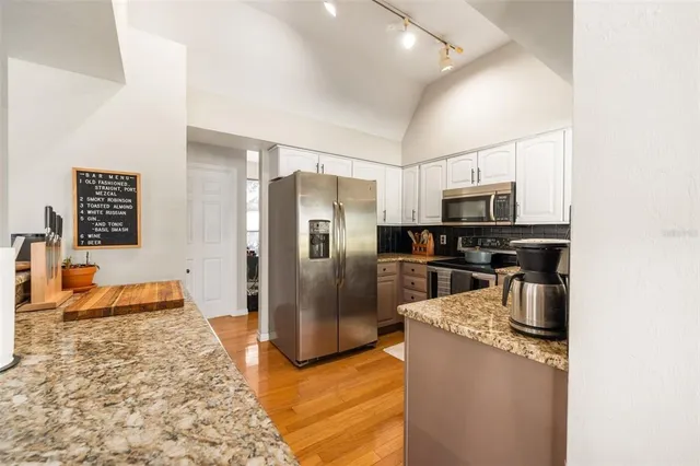a kitchen with stainless steel appliances granite countertop a refrigerator a stove and a sink