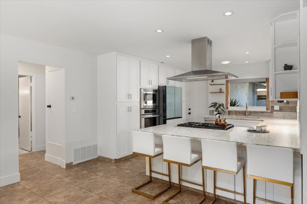 1267 Discovery Street San Marcos, CA 92078 - Photo 24 of 75 a kitchen with stainless steel appliances kitchen island a table chairs sink and cabinets