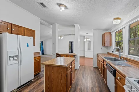 a kitchen with stainless steel appliances a stove a refrigerator a sink a oven with wooden floor and cabinets