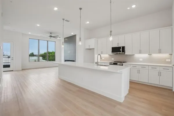 a large kitchen with granite countertop a large counter top and stainless steel appliances