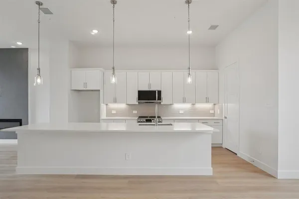 a large kitchen with kitchen island a stove a sink a center island and wooden floor