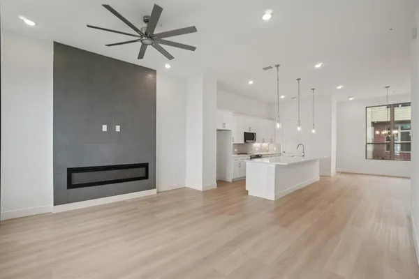 a large kitchen with kitchen island a stove a sink a refrigerator and white cabinets with wooden floor