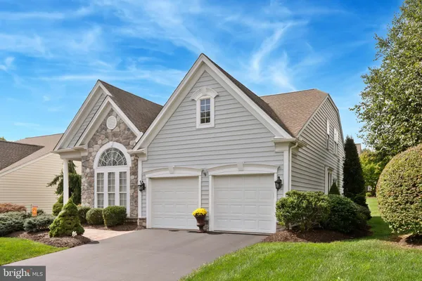 a view of a house with a small yard plants and a large tree