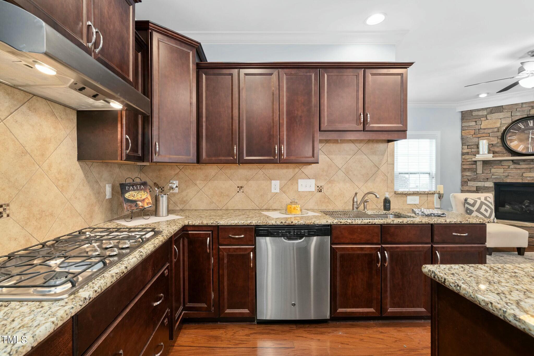 1052 Monmouth Loop Cary, NC 27513 - Photo 14 of 37 a kitchen with stainless steel appliances granite countertop a stove a sink dishwasher and cabinets with wooden floor