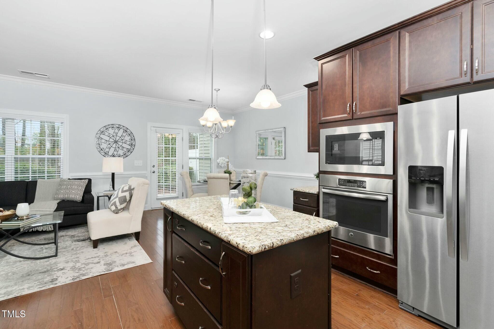 1052 Monmouth Loop Cary, NC 27513 - Photo 15 of 37 a kitchen with a refrigerator a sink dishwasher a dining table and chairs with wooden floor