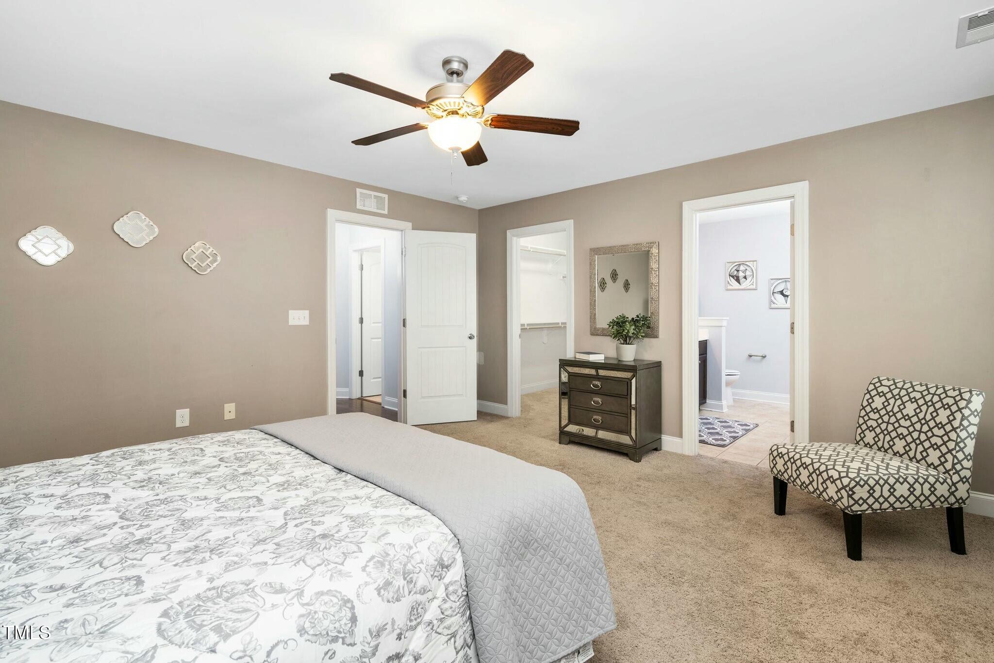 1052 Monmouth Loop Cary, NC 27513 - Photo 20 of 37 a spacious bedroom with a bed a couch and a chandelier