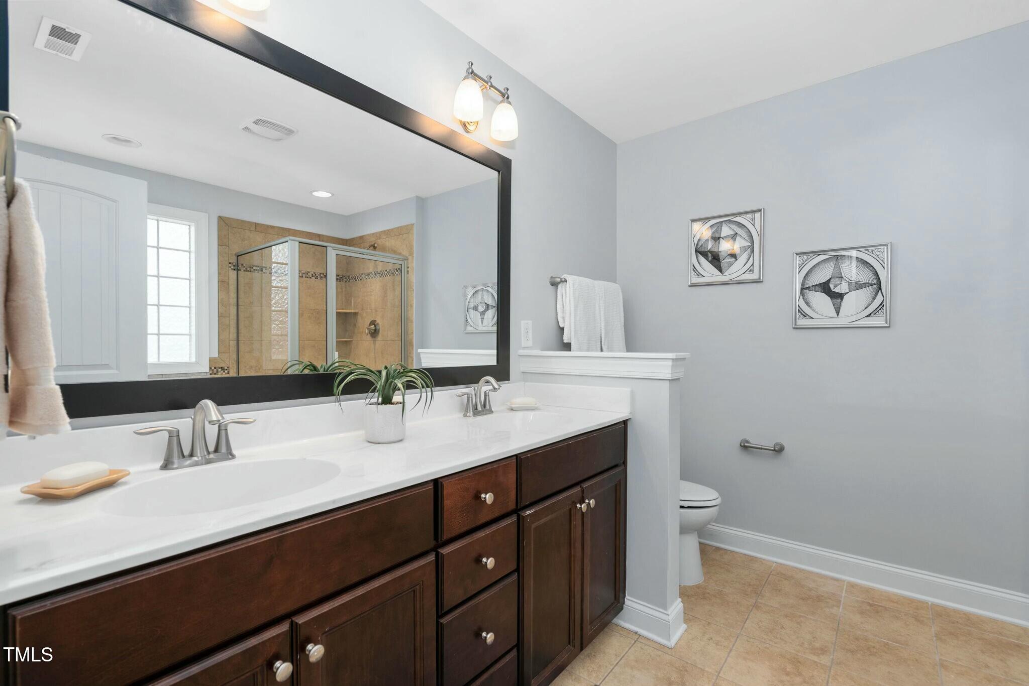 1052 Monmouth Loop Cary, NC 27513 - Photo 23 of 37 a bathroom with a double vanity sink and a mirror