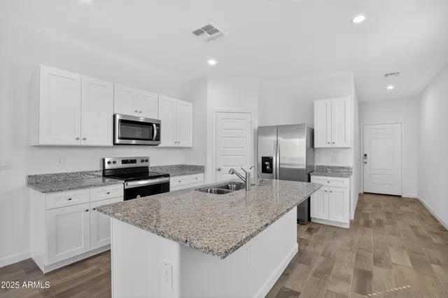 a kitchen with granite countertop a sink a counter top space stainless steel appliances and cabinets