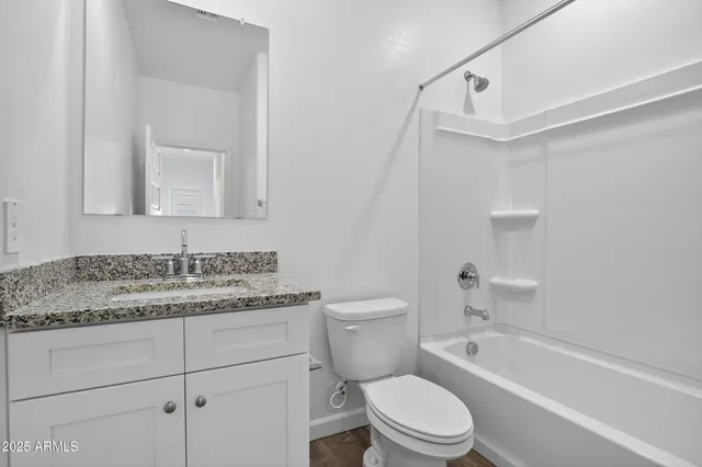a bathroom with a granite countertop toilet sink and mirror