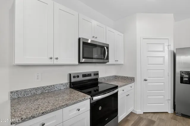 a kitchen with granite countertop white cabinets and stainless steel appliances