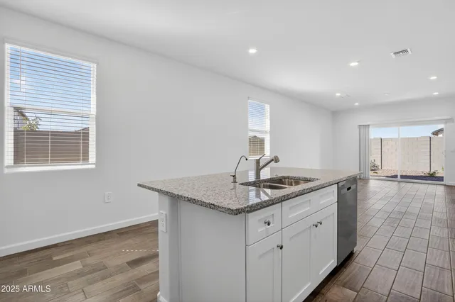 a kitchen with a sink dishwasher and cabinets with wooden floor