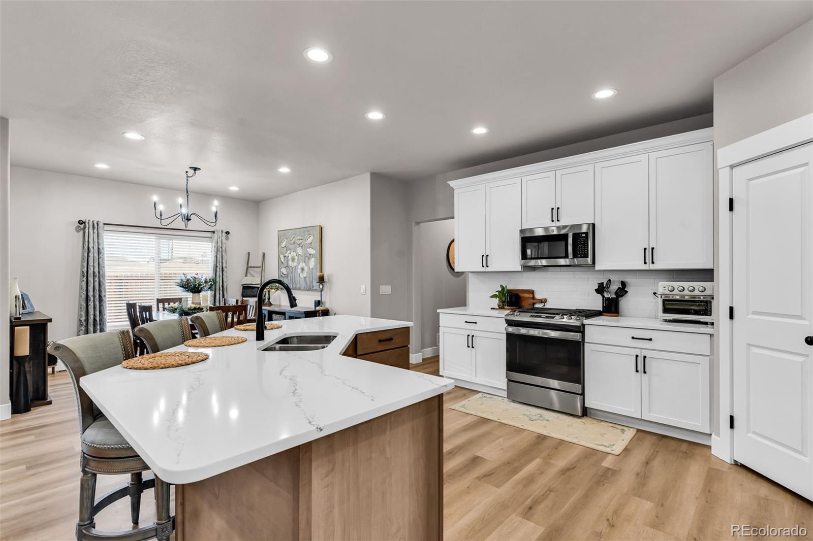 425 Miners Road Canon City, CO 81212 - Photo 14 of 33 a large kitchen with kitchen island a stove a sink a refrigerator and white cabinets with wooden floor