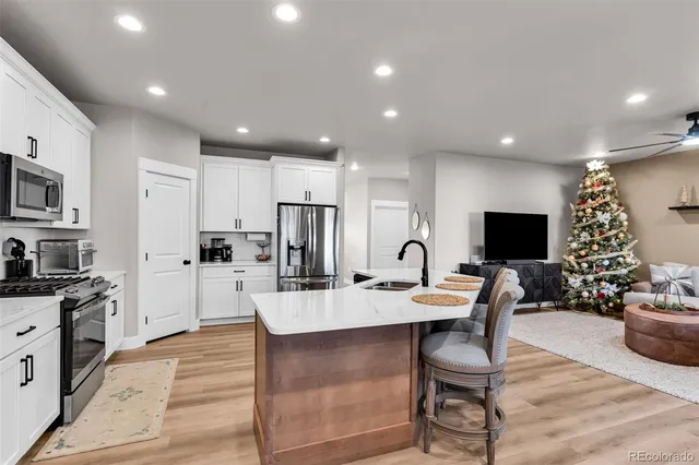 a living room with stainless steel appliances furniture a rug kitchen view and a chandelier
