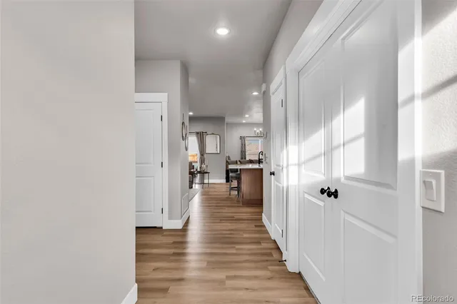 a view of a hallway with wooden floor and a bathroom