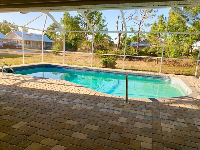 a view of a swimming pool with a chair and tables in the patio