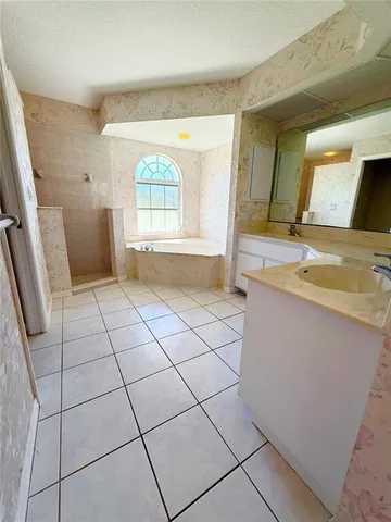 a spacious bathroom with a granite countertop sink a mirror and a bathtub