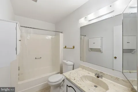 a bathroom with a granite countertop sink a toilet and shower