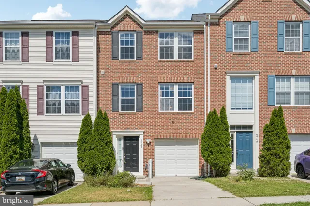 a view of a brick house with a yard plants and a table and chairs