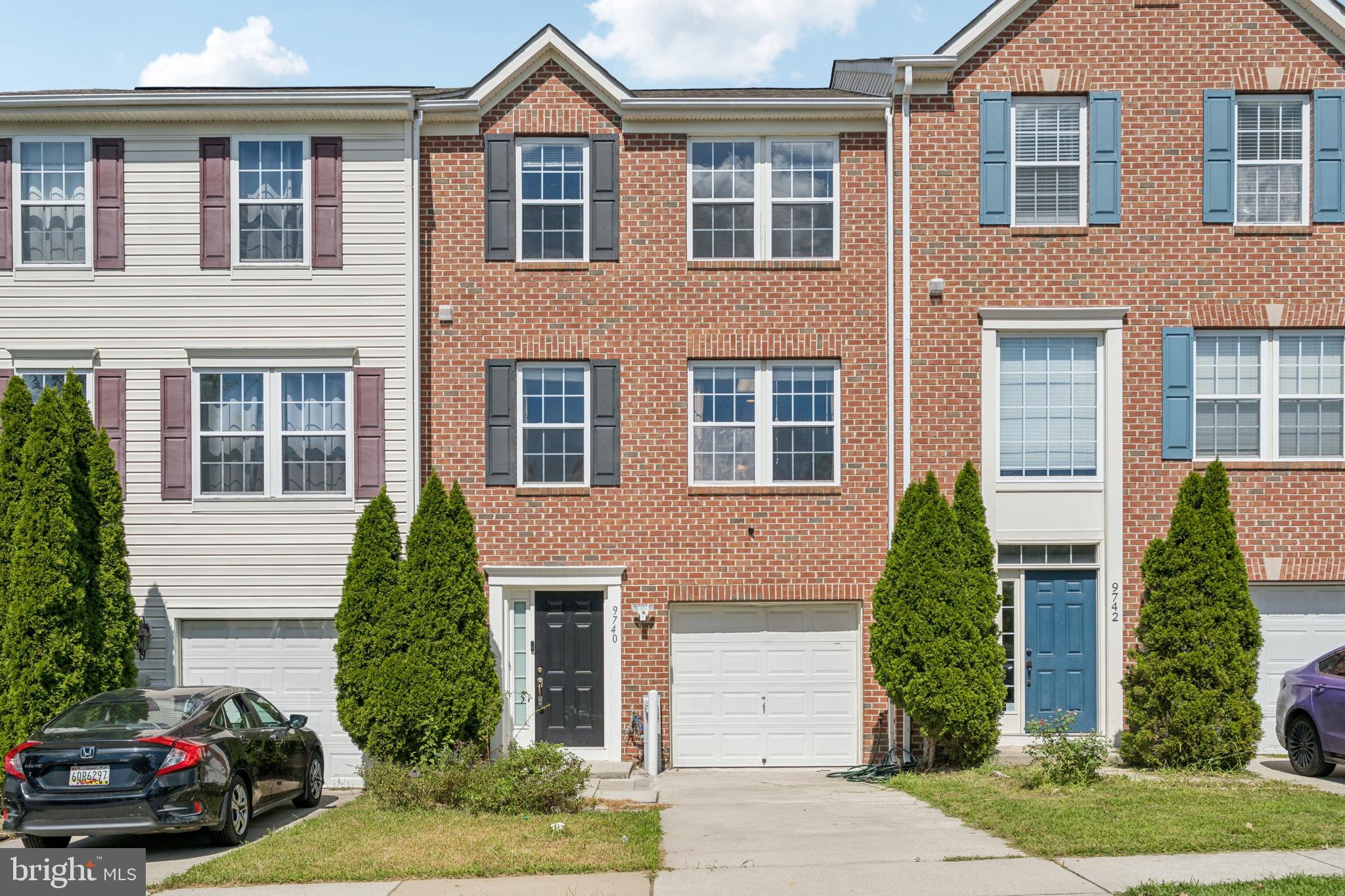 a view of a brick house with a yard plants and a table and chairs