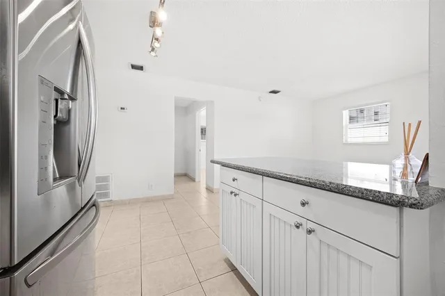 a kitchen with granite countertop a refrigerator and cabinets