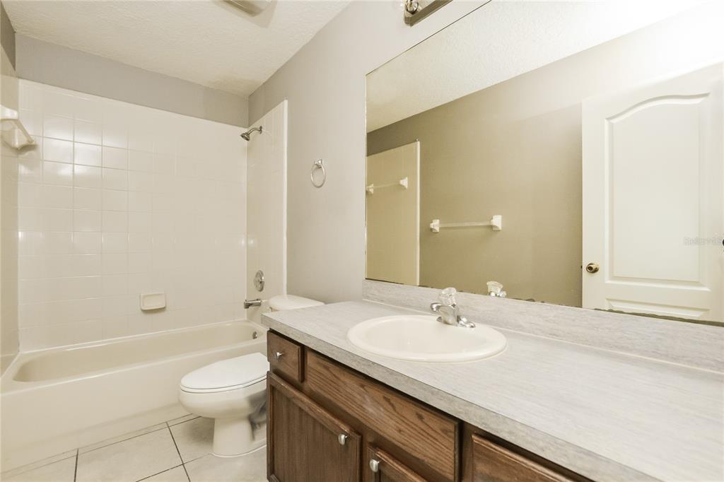 713 Willow Run Street Minneola, FL 34715 - Photo 11 of 16 a bathroom with a granite countertop sink a toilet and shower