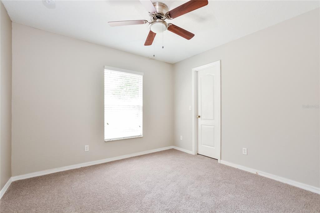 713 Willow Run Street Minneola, FL 34715 - Photo 12 of 16 an empty room with windows and fan