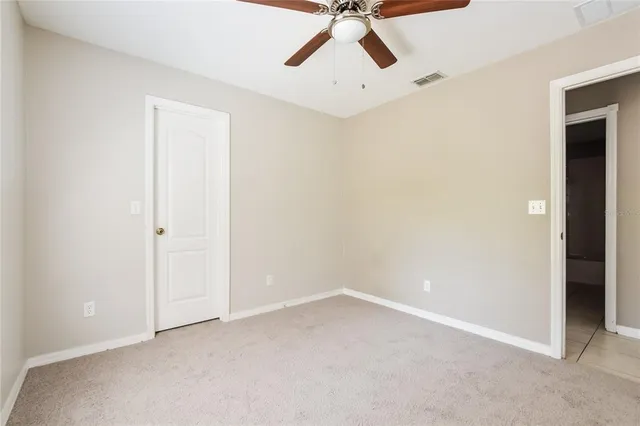an empty room with a ceiling fan and carpet