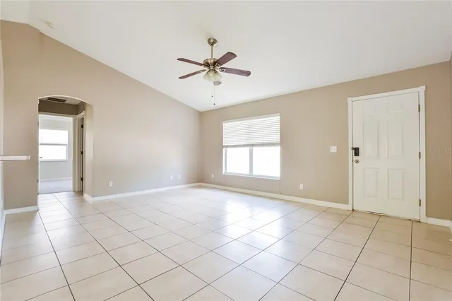 a view of an empty room with window and chandelier fan