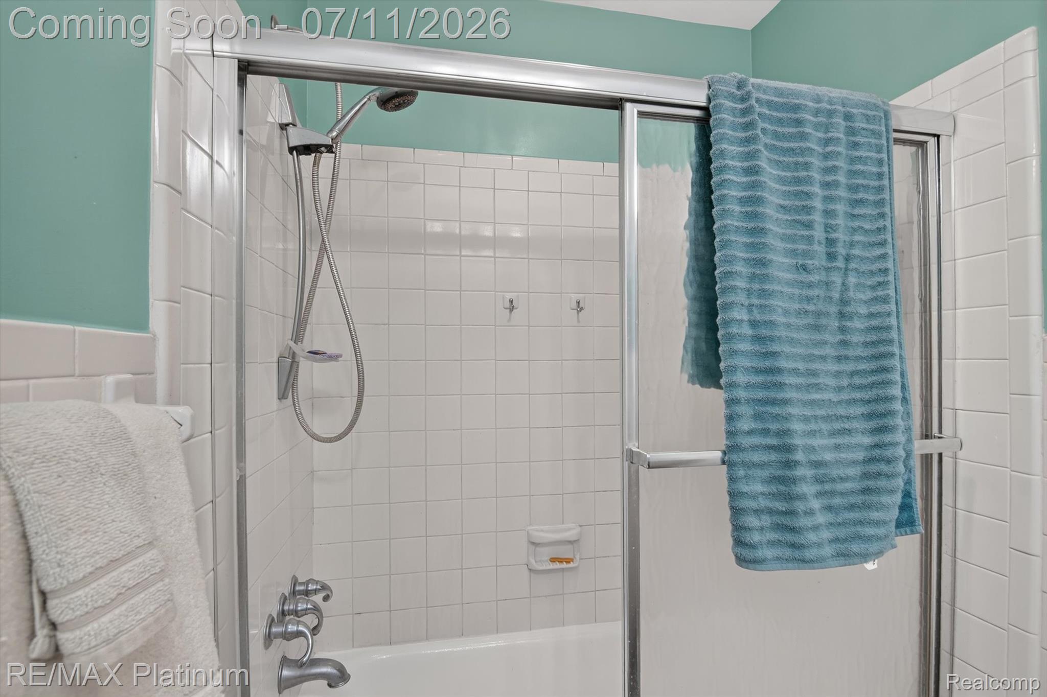 13365 North Territorial Road Gregory, MI 48137 - Photo 32 of 52 Bathtub and shower combination featuring white square tiling, a chrome shower fixture, and a silver-framed glass shower enclosure