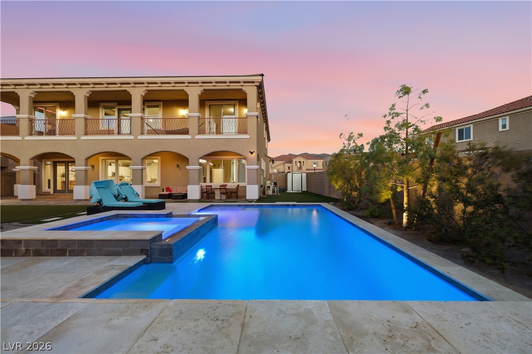 2737 Tarbert Street Henderson, NV 89044 - Photo 3 of 60 An inviting pool and spa beckon under a vibrant evening sky, complementing the home's elegant architecture.
