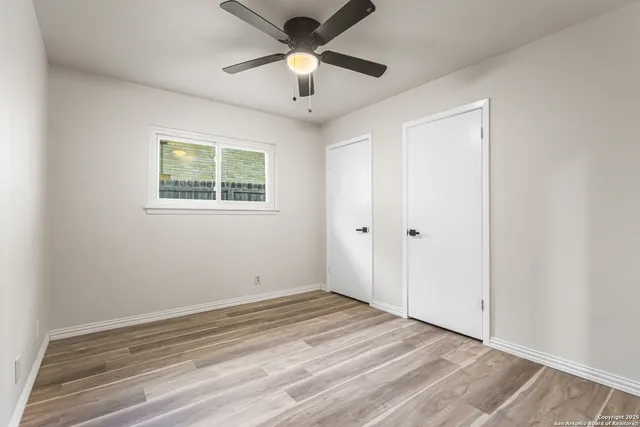 a view of empty room with wooden floor and ceiling fan