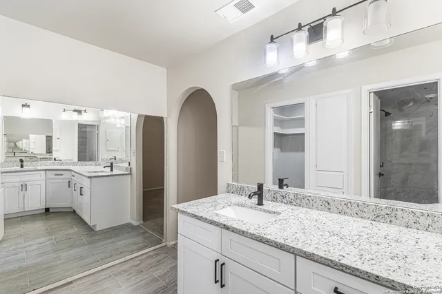 a bathroom with a granite countertop double vanity sink and mirror