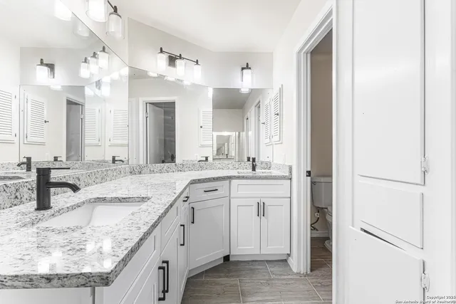 a spacious bathroom with a granite countertop sink and a mirror