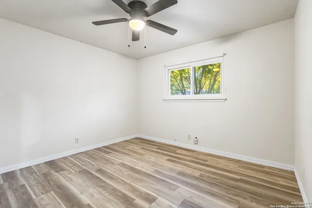 an empty room with a window and ceiling fan