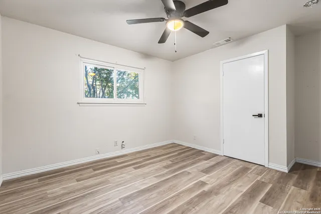 an empty room with a window and a ceiling fan