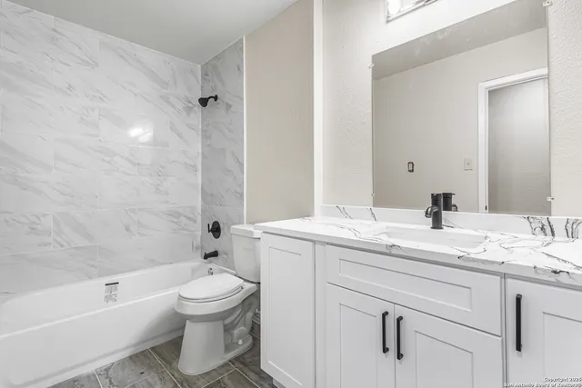 a bathroom with a granite countertop sink toilet a large mirror a bathtub and shower