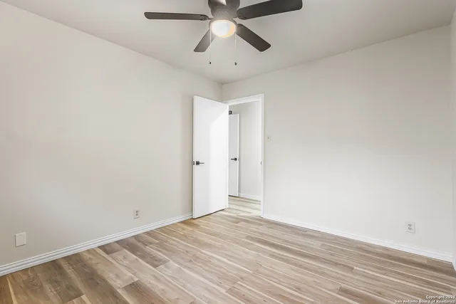 a view of empty room with wooden floor and ceiling fan