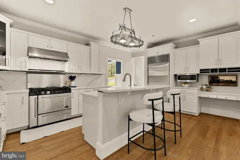 a kitchen with stainless steel appliances a table and chairs in it