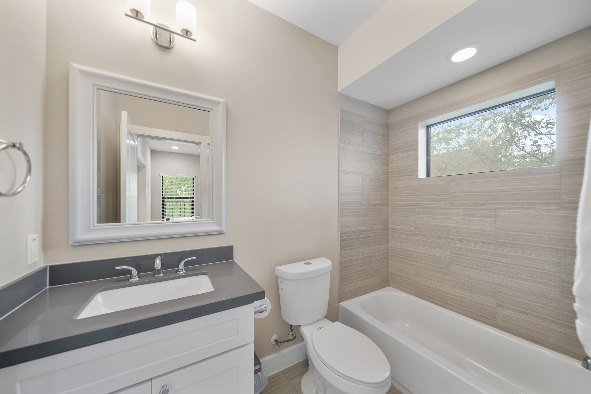 1824 Bonner Street Houston, TX 77007 - Photo 36 of 39 Serving as the home's third full bath, this bath includes a painted Shaker-style cabinet supporting a quartz counter with integrated back splash, framed mirror with lighting above, a ceramic tile surrounded combination tub/shower with window above & tile flooring.