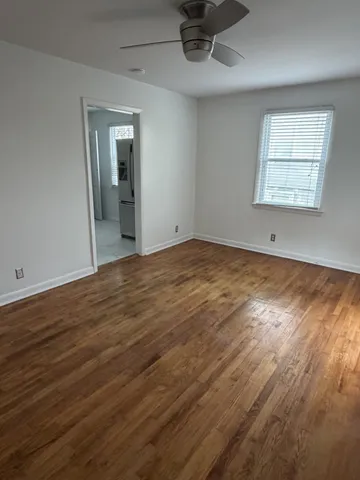 an empty room with wooden floor cabinet and windows