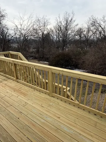 a view of a balcony with wooden floor and fence